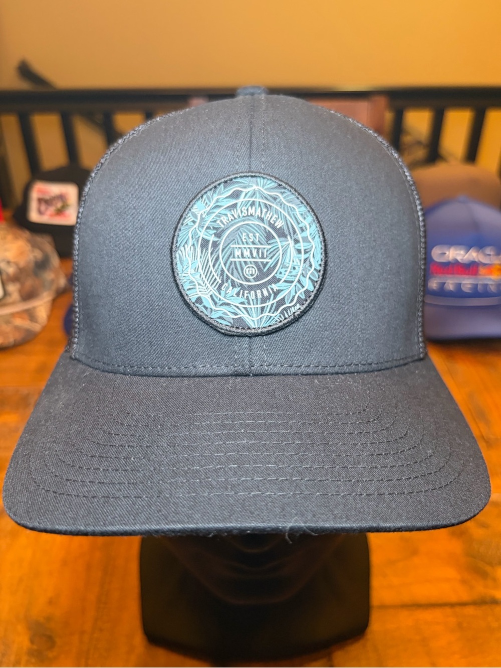 Travis Mathew Black Trucker Hat with Teal Patch